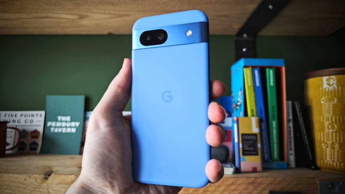 Pixel 8a in blue held infront of a shelf