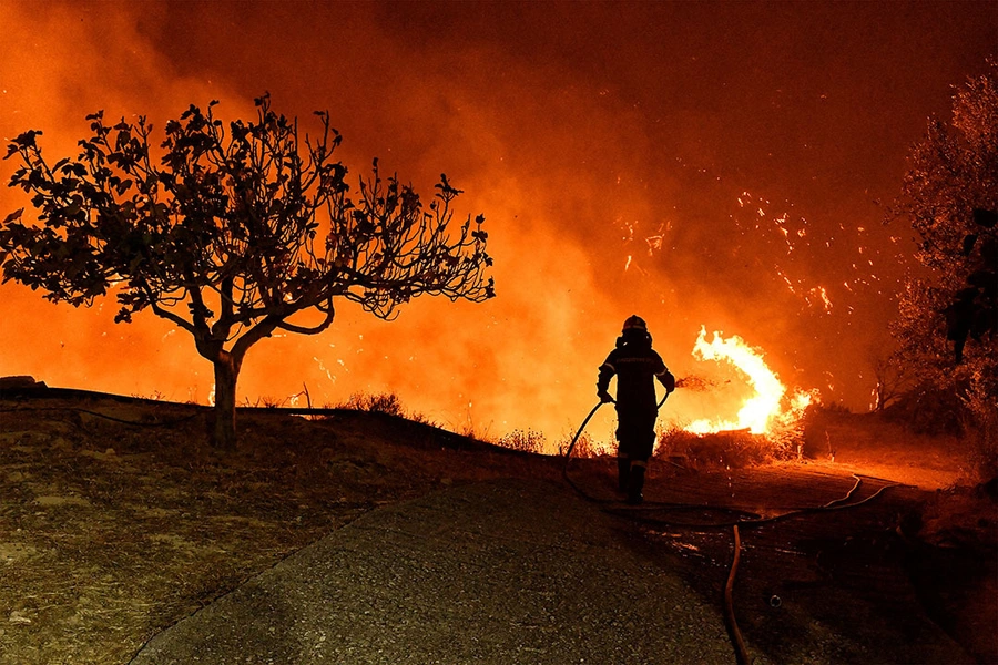 A firefighter tries to extinguish a wildfire burning next to the village of Kallithea, near Corinth, Greece.