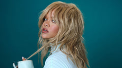 Rihanna in blonde hair on a teal background.