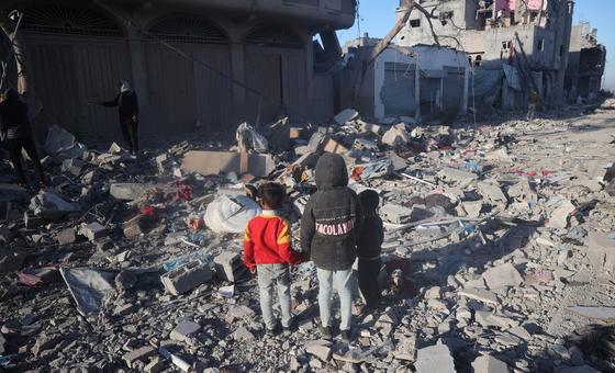 Three children stand amidst the rubble of their destroyed home in Rafah.