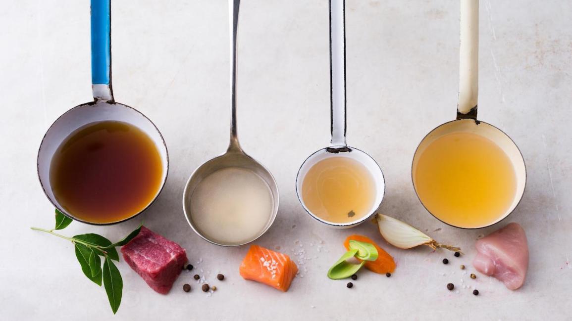 ladles of bone broth posed beside raw meat