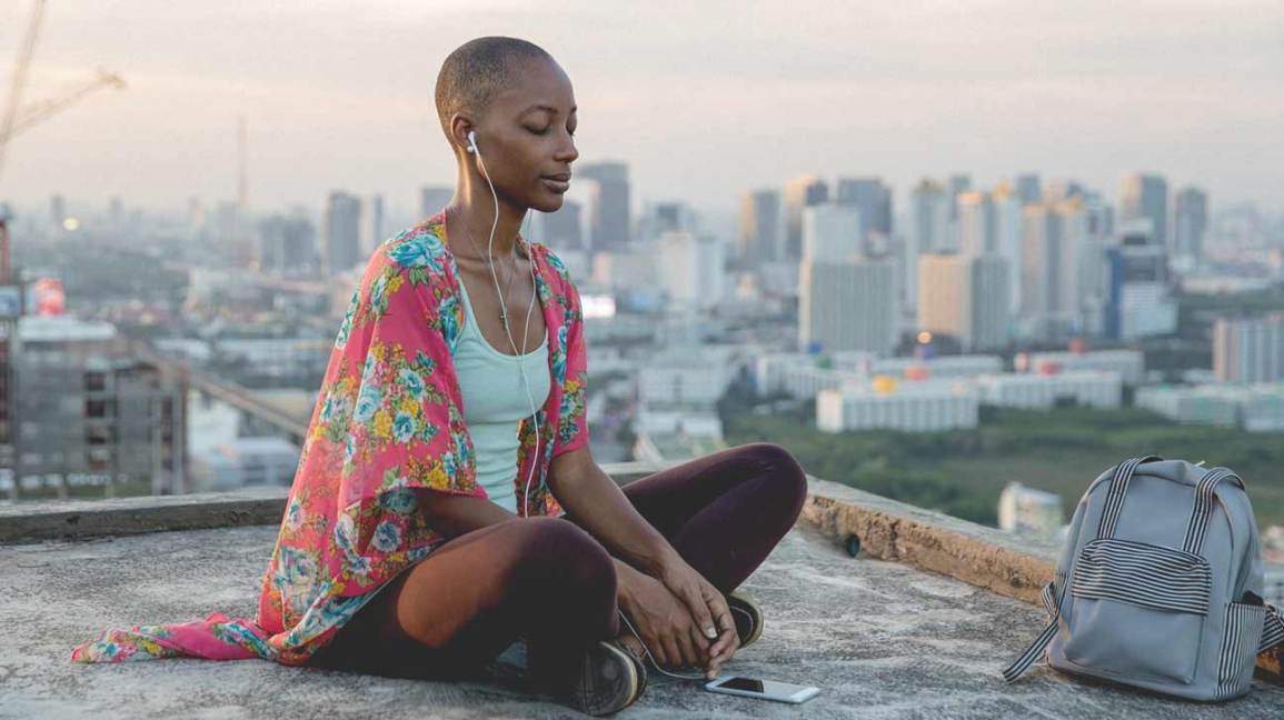 woman meditating on a rooftop in a city