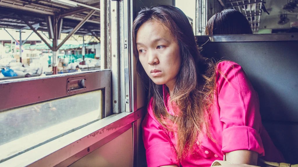 woman in pink shirt looking out train window