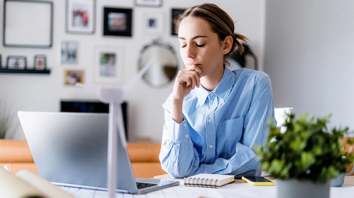 Woman working at a laptop closes her eyes