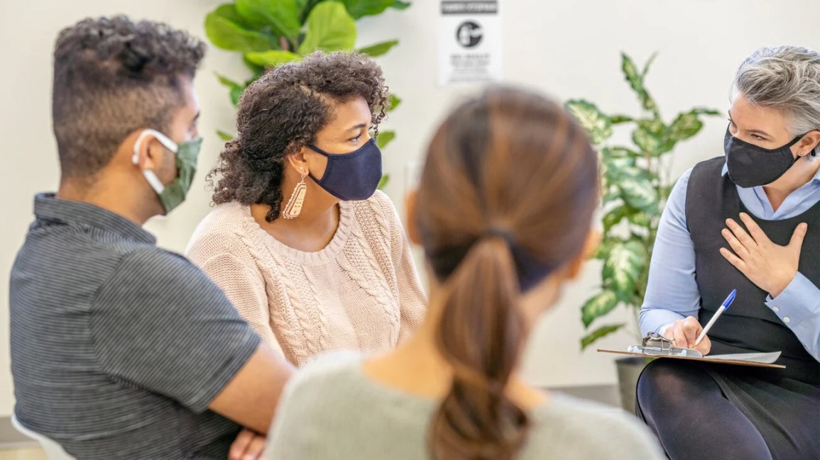 people sitting in group therapy wearing masks