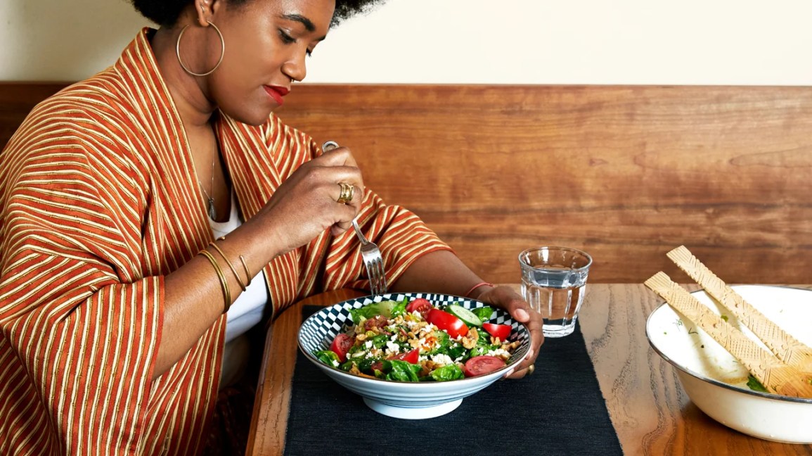 Woman seated at a table eating a salad