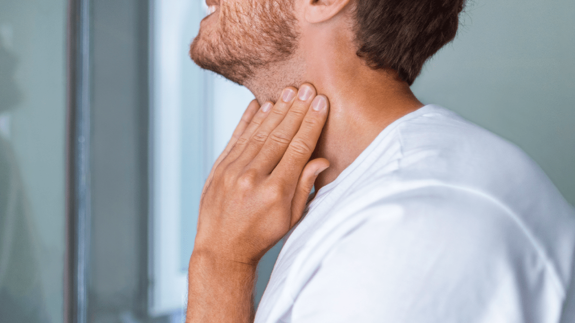 Man performs home self-check on thyroid gland at the side of his neck. People with diabetes often experience thyroid disorders.