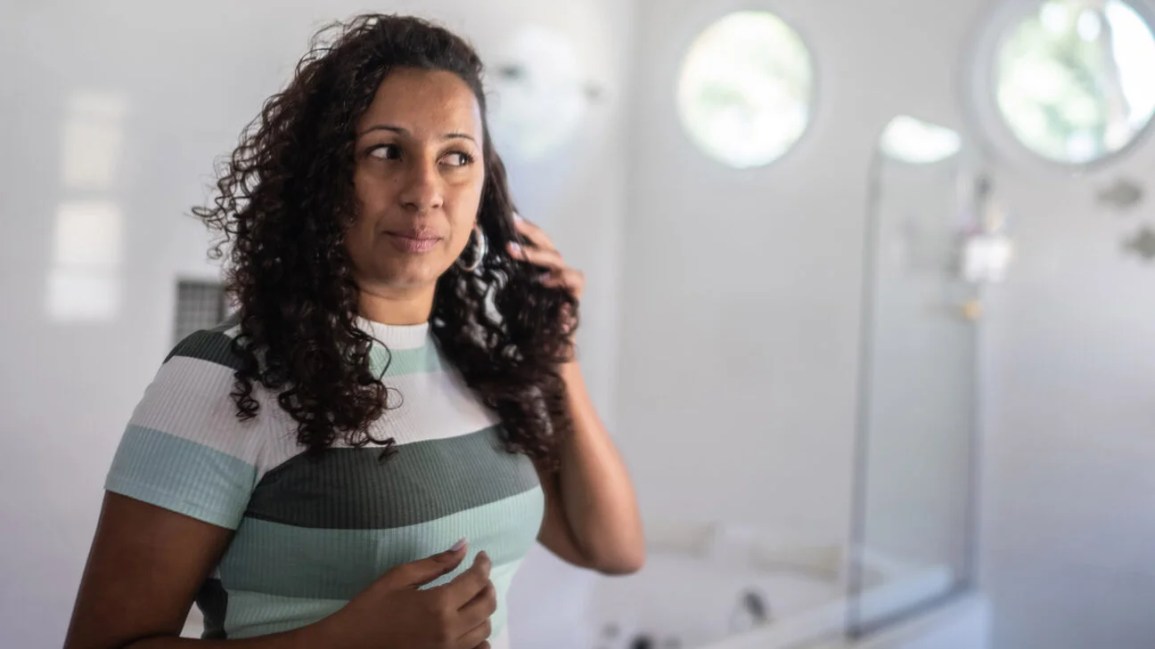 Woman looking at her hair in the mirror.