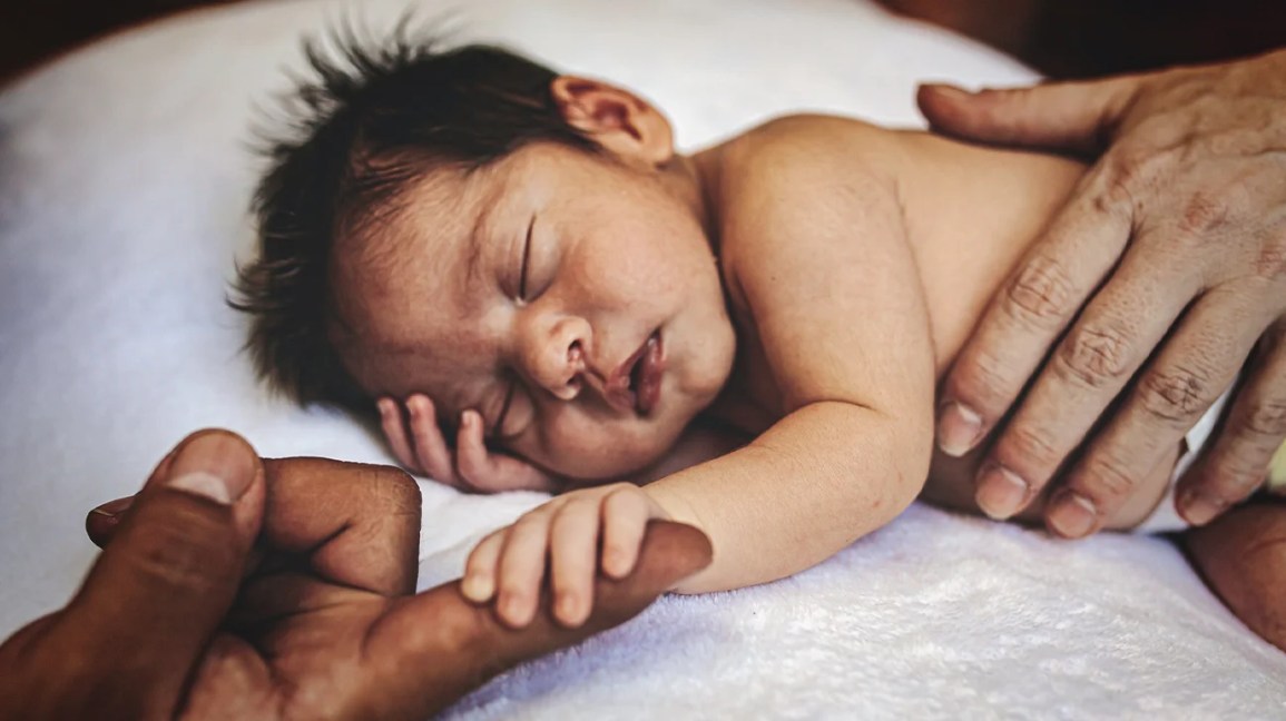 Baby holding parent finger