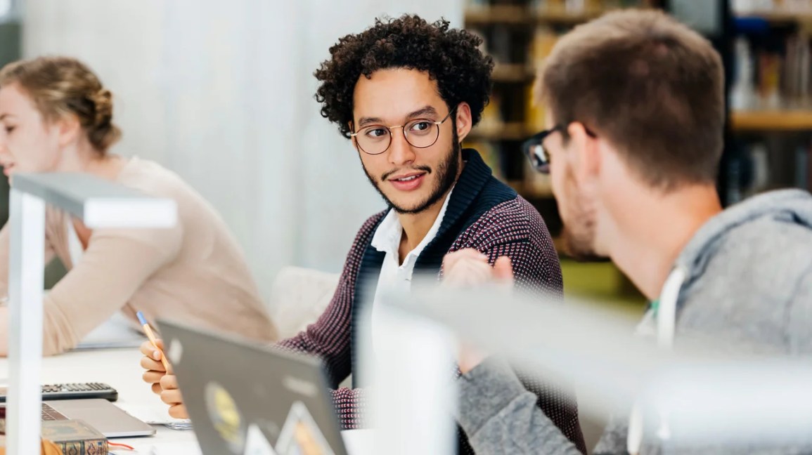 Two people sit and talk in open office workspace 1