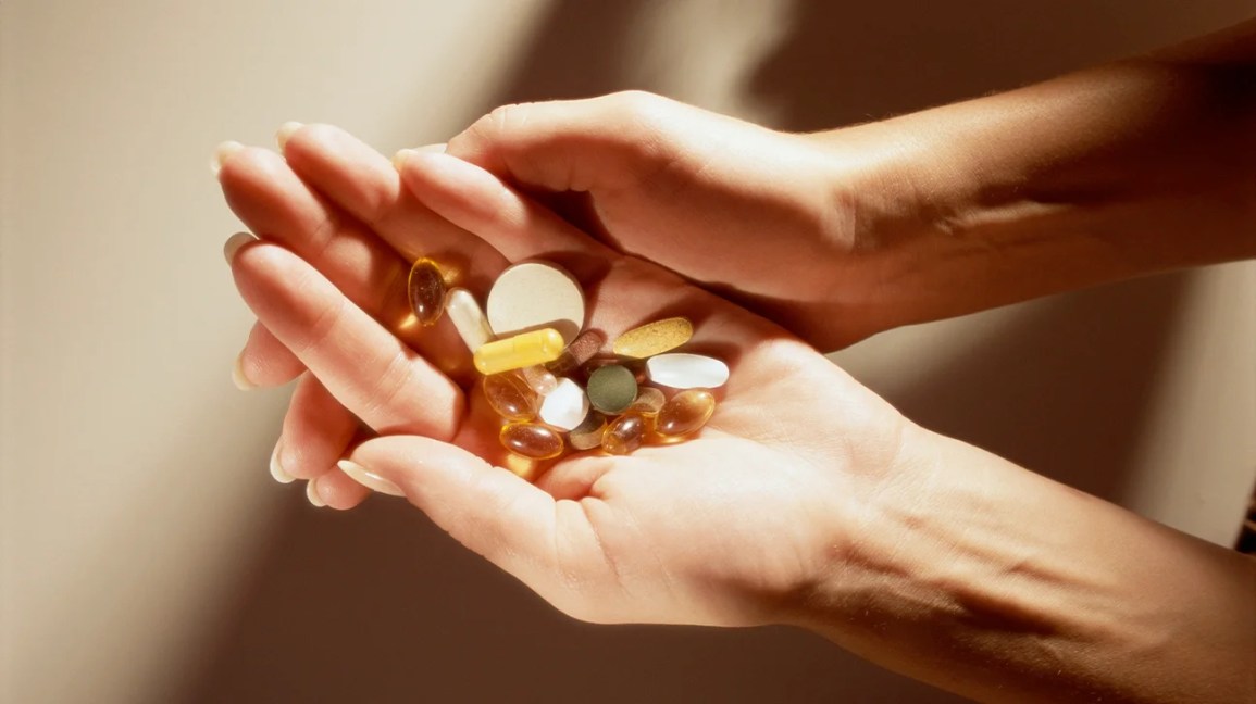 A close-up of a hand holding many pills.