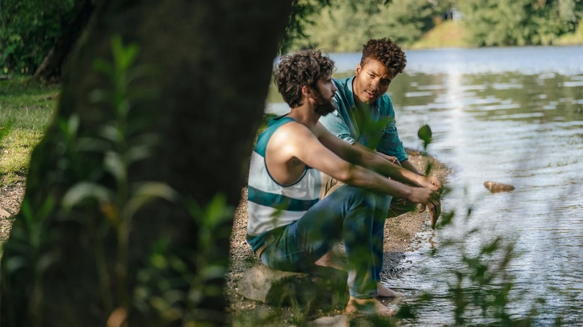 Two males talking by the water.