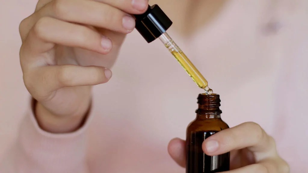 a woman holding a tub of essential oils that can used to treat symptoms of menopause