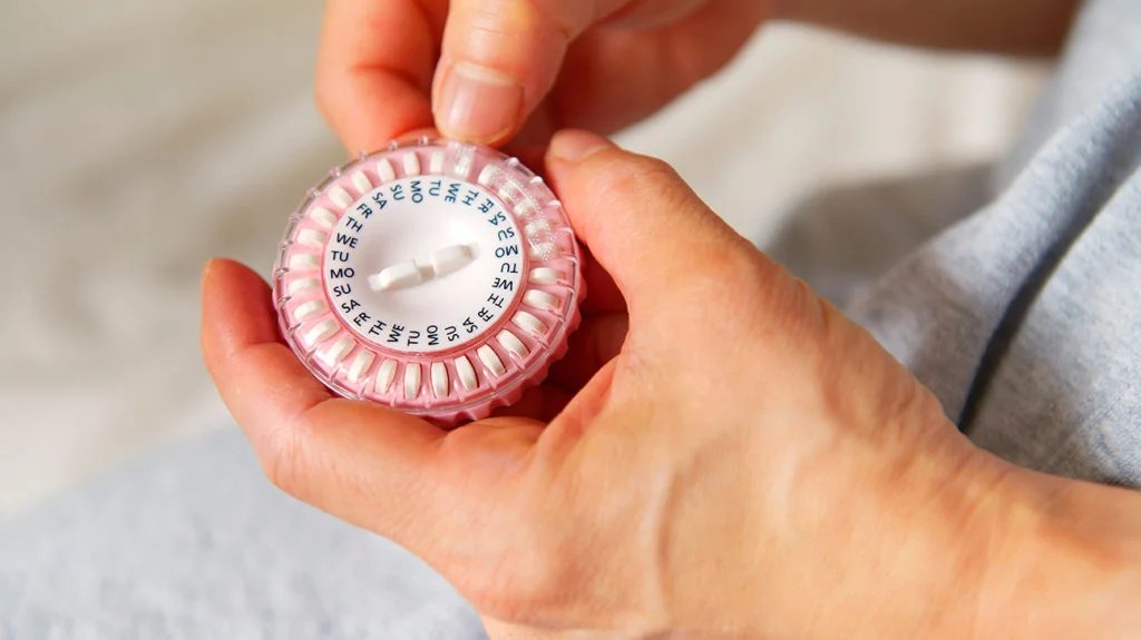 a woman using a dispenser to keep track of her Hormone replacement therapy tablets