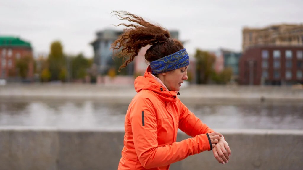 A woman using a fitness tracker to measure her fitness and health, which can be referred to as biohacking.