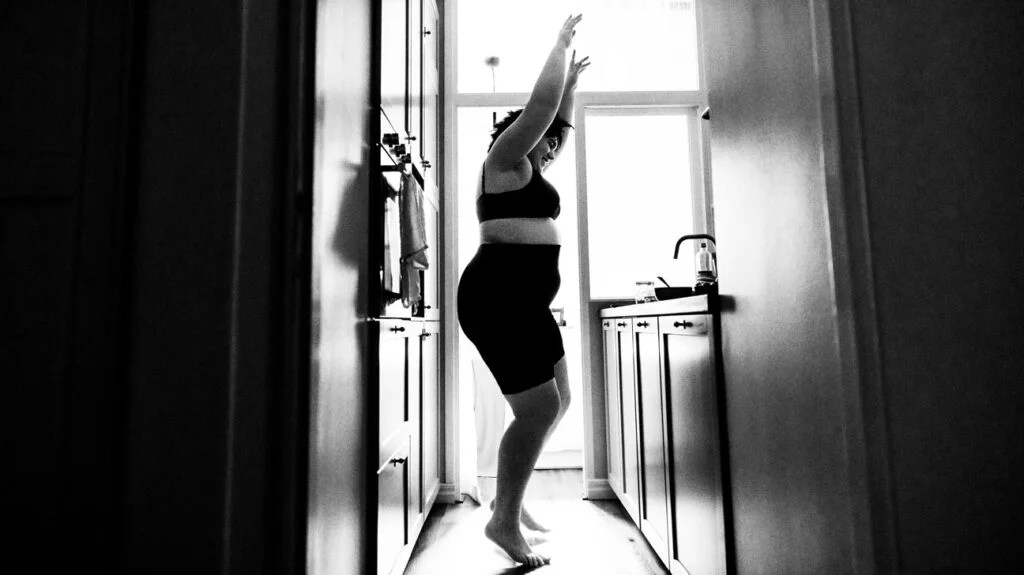 Black and white image of a female dancing in the kitchen