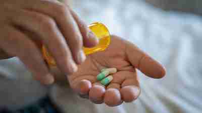 Closeup of man hand pouring capsules from a pill bottle into hand. Senior man taking daily medicine to consume. Close up of male hands taking daily dose of drug.