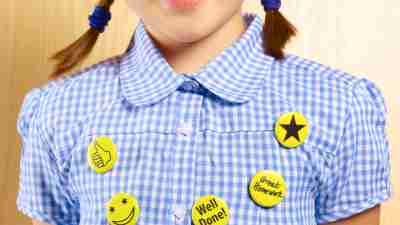 8 year old school girl with good work reward button badges.