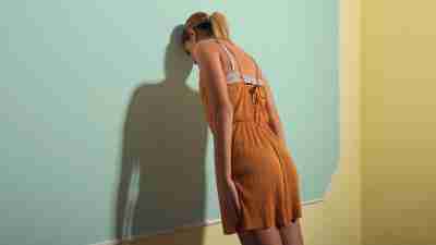 Rear View Of Sad Woman Leaning On Wall