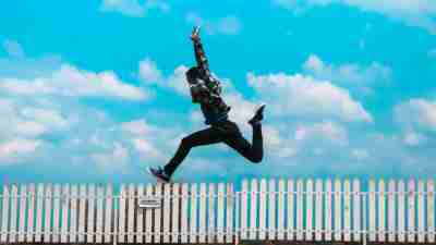 A photograph of a man jumping over a white fence, breaking free from ADHD paralysis.