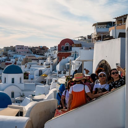 Turistas tomando fotografías y selfis en la ciudad de Oia (Santorini) ante sus casas encaladas e iglesias con cúpulas azules.
