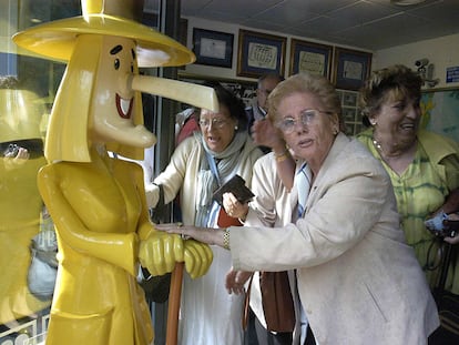 Una mujer toca las manos del muñeco que da nombre a la administración de lotería de Sort, "La Bruixa d'Or".