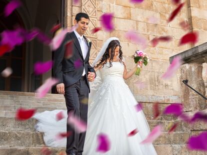 Una pareja de recién casados recibe una lluvia de pétalos de rosa el día de su boda.