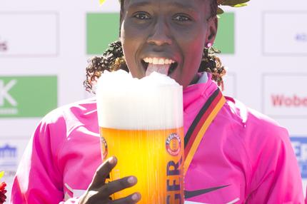 Florence Kiplagat, Gewinnerin des Berlin Marathon 2013, feiert mit einem Glas Bier