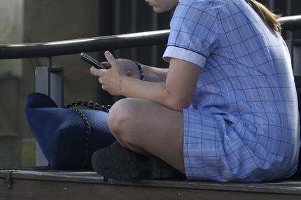 Social Media: Ein Mädchen in Schuluniform in Sydney liest auf ihrem Handy.