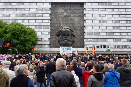 Neonazis: Demonstrators gather in front of the Karl Marx monument, where a poster is fixed reading "Chemnitz is neither grey nor brown" during a protest organised by the right-wing populist "Pro Chemnitz" movement, the far-right Alternative for Germany (AfD) party and the anti-Islam Pegida movement, on September 1, 2018 in Chemnitz, eastern Germany. - The demonstration was organised in a reaction to a knife killing, allegedly by an Iraqi and a Syrian, that set off anti-immigrant mob violence. (Photo by John MACDOUGALL / AFP) (Photo credit should read JOHN MACDOUGALL/AFP via Getty Images)