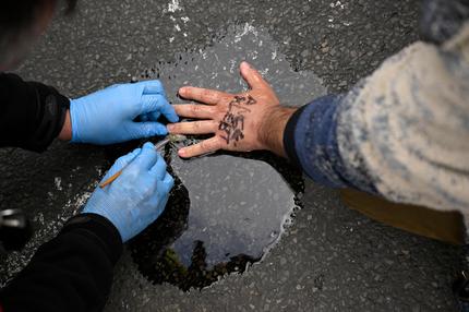 Klimaaktivisten: Ein Klimaaktivist der Letzten Generation hat seine Hand auf den Asphalt geklebt.