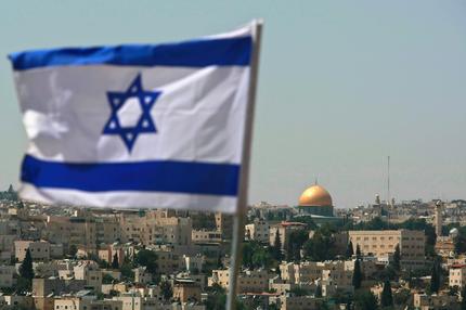 Nationalitätsgesetz: JERUSALEM - AUGUST 18:  An Israeli flag flies from the Kidmat Zion Jewish settlement community on the outskirts of the Arab village of Abu Dis, where the Old City with its golden Dome of the Rock Islamic shrine is seen in the background, August 18, 2008 in East Jerusalem, Israel. The settlement, a stand-alone apartment building which houses a number of families, is a former Arab home purchased by the Ateret Cohanim organization which is dedicated to expanding Jewish settlement in East Jerusalem, the half of the city that Israel captured from Jordan in the 1967 Six Day War.  (Photo by David Silverman/Getty Images)