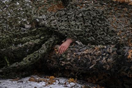 Krieg in der Ukraine: SUMY REGION, UKRAINE - DECEMBER 6, 2024: A Ukrainian soldier from Ukraine's 95th Brigade adjusts a camouflage net on military equipment in Sumy region, Ukraine. (Photo by Serhiy Morgunov/For The Washington Post via Getty Images)