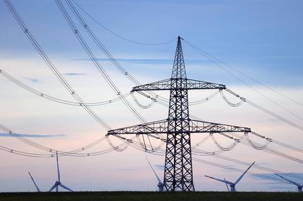 Stromversorgung: Windräder stehen hinter dem Mast einer Stromtrasse. Ungeachtet immenser Kosten liegt die Energiewende in Deutschland nach einer neuen Studie in mehreren Bereichen weit hinter den politischen Zielen zurück. (zu dpa-KORR: «Prognos-Studie: Energiewende lahmt immer noch»). +++ dpa-Bildfunk +++