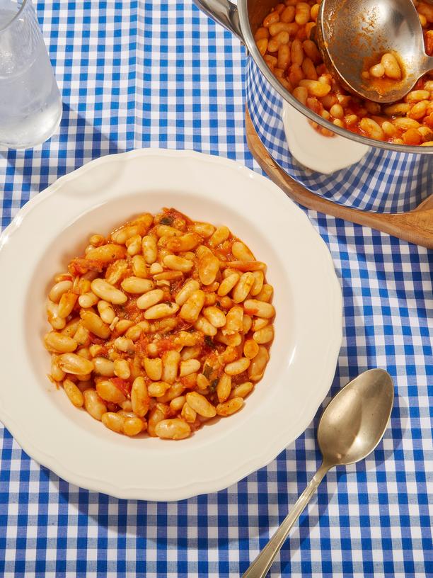 Baked Beans: "Table with a blue checkered tablecloth, and on it, a plate of baked beans, along with a pot, a plate of bread, and a glass of water."