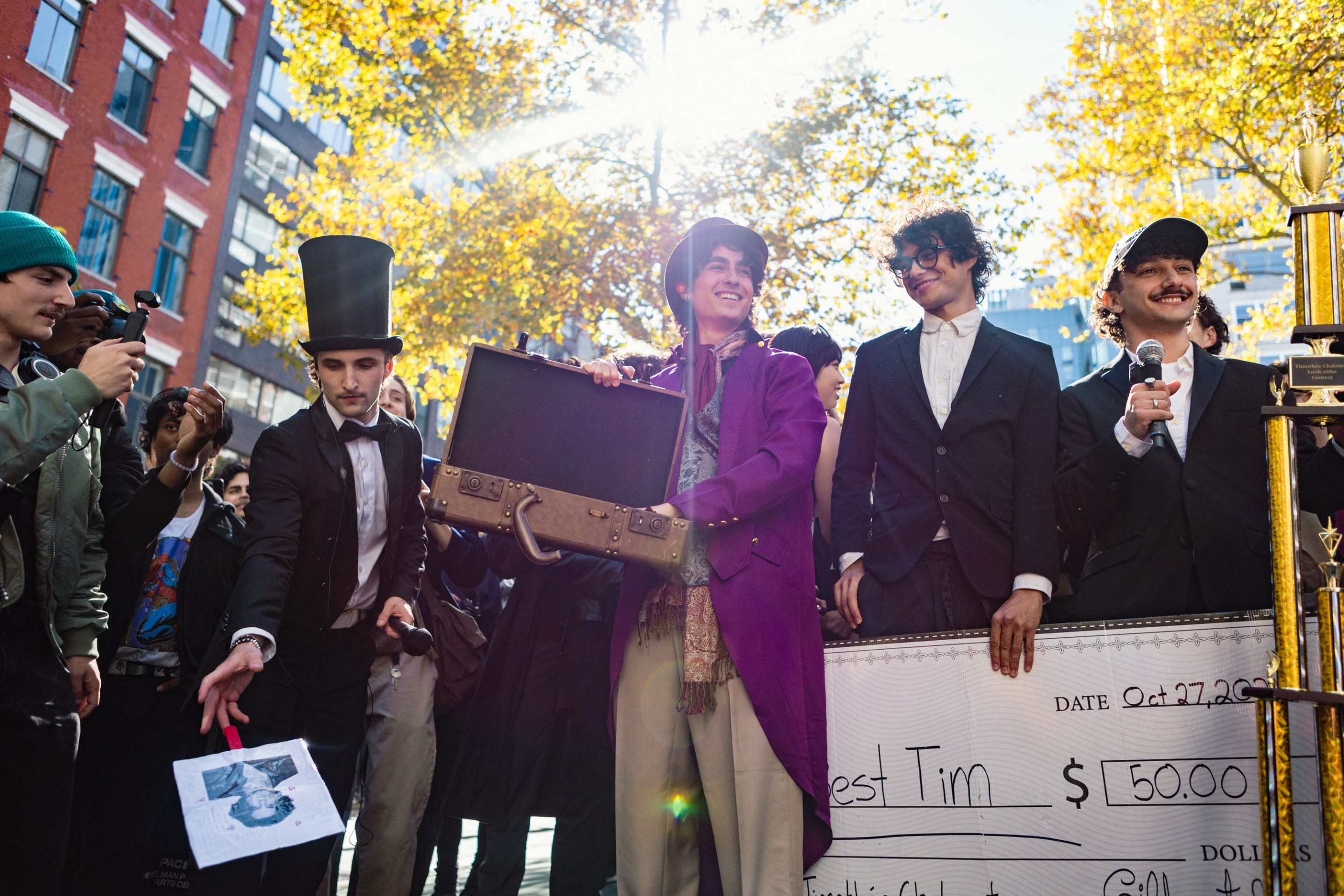 A Timothee Chalamet lookalike in a Wonka costume showcases an empty briefcase