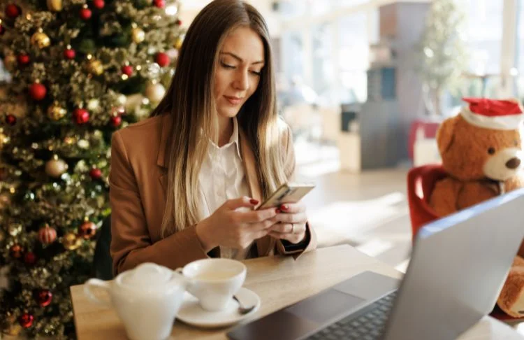 Holiday email examples - Woman looks at phone with holiday background.