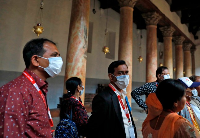 People wearing masks visit the Church of the Nativity, revered as the birthplace of Jesus Christ, in the West Bank city of Bethlehem on March 5, 2020. - The Palestinian health ministry called for local churches, mosques and other institutions to close after suspected cases had been detected at the hotel in the Bethlehem area, the first in the Palestinian territories. (Photo by Ahmad GHARABLI / AFP) (Photo by AHMAD GHARABLI/AFP via Getty Images)