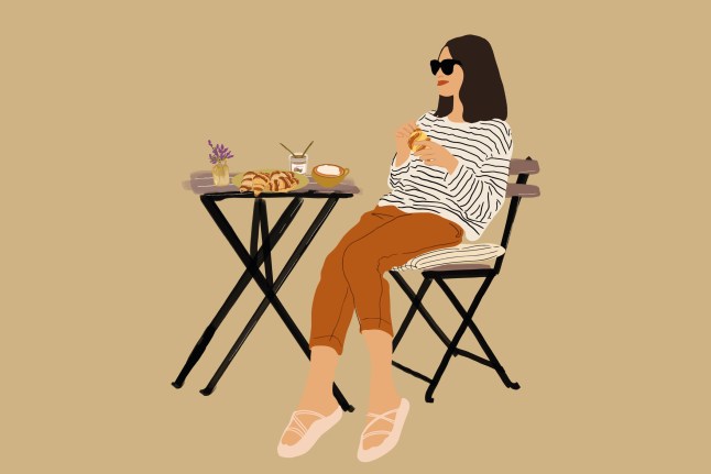 Cheerful woman sitting at a table with croissant.