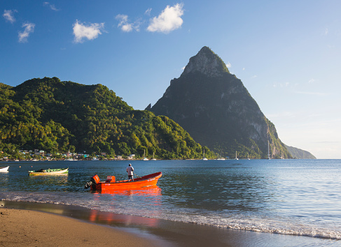 View across Soufriere Bay to Petit Piton, colourful fishing boat moored offshore, Soufriere, St Lucia