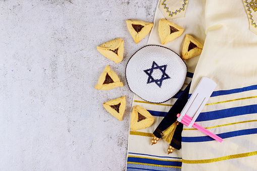 Jewish carnival Purim celebration on hamantaschen cookies, noisemaker and mask with parchment