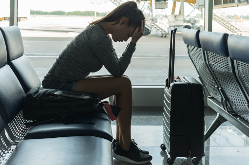 A passenger waiting at the airport terminal stressed out at tired.