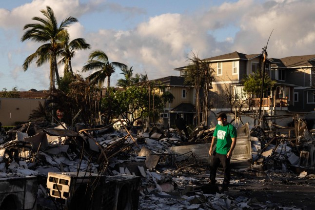 TOPSHOT - A Mercy Worldwide volunteer makes damage assessment of charred apartment complex in the aftermath of a wildfire in Lahaina, western Maui, Hawaii on August 12, 2023. Hawaii's Attorney General, Anne Lopez, said August 11, she was opening a probe into the handling of devastating wildfires that killed at least 80 people in the state this week, as criticism grows of the official response. The announcement and increased death toll came as residents of Lahaina were allowed back into the town for the first time. (Photo by Yuki IWAMURA / AFP) (Photo by YUKI IWAMURA/AFP via Getty Images)