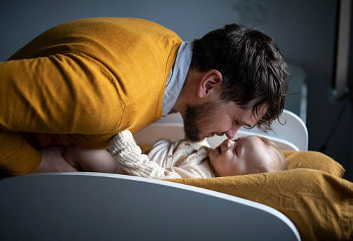 Father changing clothes and diapers to his baby boy at home.