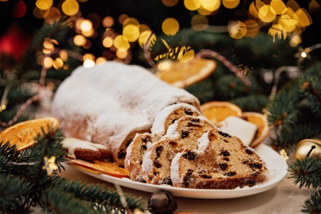 Christmas stollen on wooden background. Traditional Christmas German dessert cut into pieces. Cake with nuts, raisins with marzipan and dried fruit on cutting board. baking for Xmas