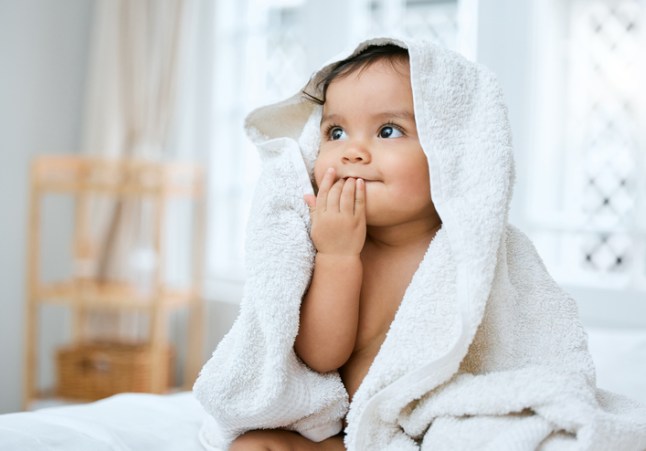 Shot of an adorable baby covered in a towel after bath time