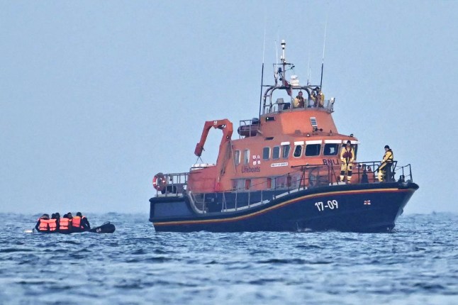 TOPSHOT - Crew aboard Royal National Lifeboat Institution (RNLI) Severn class lifeboat, the City of London II, pick up migrants in an inflatable boat who were travelling across the English Channel, bound for Dover on the south coast of England. - More than 45,000 migrants arrived in the UK last year by crossing the English Channel on small boats. (Photo by Ben Stansall / AFP) (Photo by BEN STANSALL/AFP via Getty Images)