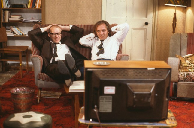 Comic actors Adrian Edmondson (left) and Rik Mayall watching television in scene from episode 'Contest' of the BBC television sitcom 'Bottom', June 24th 1990. (Photo by Don Smith/Radio Times/Getty Images)