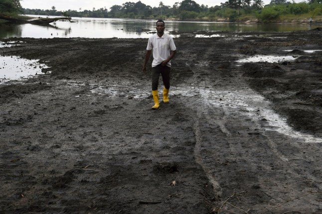 A farmer walks on a marshy shore of a river polluted by oil spills at B-Dere, Ogoniland in Rivers State on August 23, 2021. - Oil firm Shell has agreed to compensate the Ejamah community and three villages in Ogoni community in southern oil and gas-rich Niger delta, which recently won $11 million in compensation to the community over a 1970's spill that polluted over 225 hectares of their farmlands and fishing waters. (Photo by PIUS UTOMI EKPEI / AFP) (Photo by PIUS UTOMI EKPEI/AFP via Getty Images)