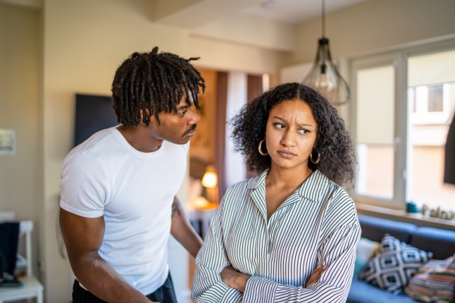 A man leans in to a woman who has her arms folded. They look to be having an argument